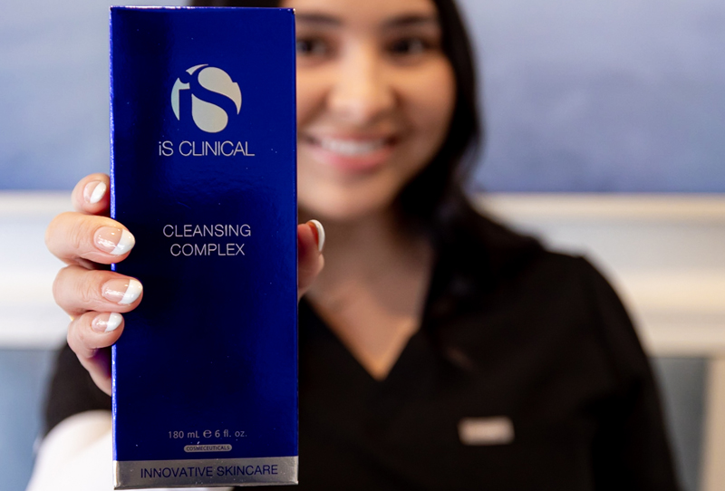 a woman holding up a blue box of Is Clinical product